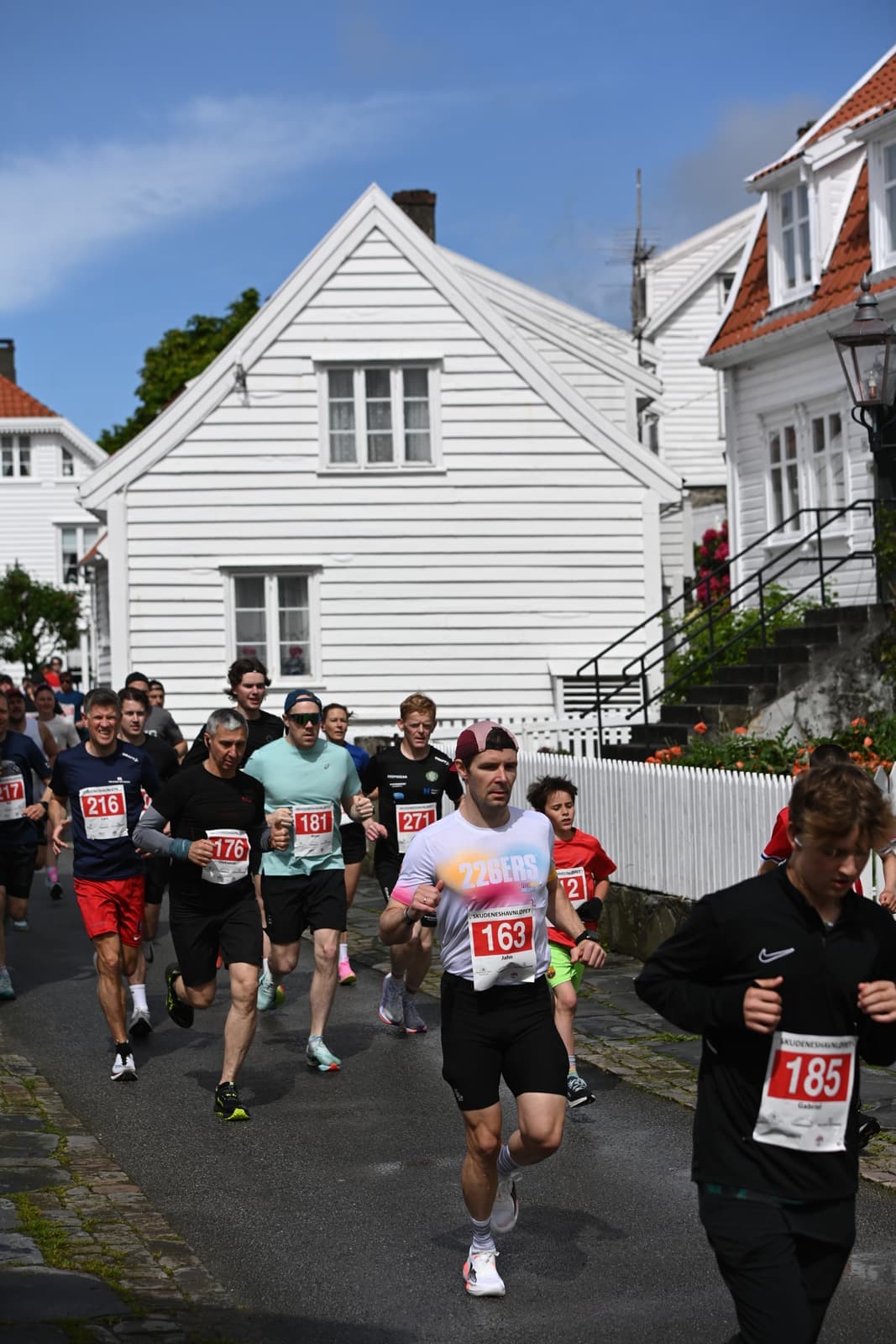 Løpere i full fart mellom de hvitmalte trehusene i Gamle Skudeneshavn